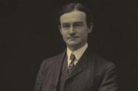 A white man wearing suit and tie looking at the camera